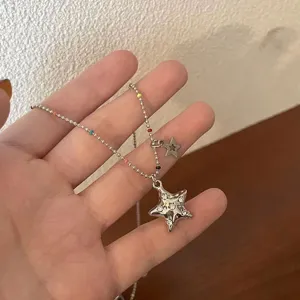 Gros plan sur le pendentif étoile et le collier de perles colorées, détail chic et élégant.