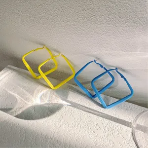 Detailopname van vierkante creoolse oorbellen in snoepkleur, felgeel en blauw, chique stijl.