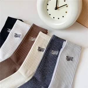 Vue détaillée de chaussettes mi-hautes côtelées pour hommes en coton avec lettres brodées.