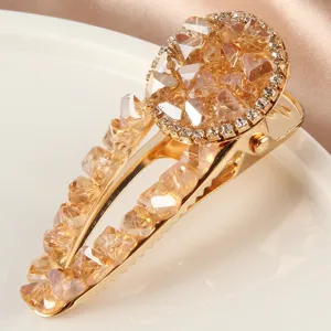 Gros plan sur la pince à cheveux dorée en cristal, ornée de strass champagne étincelants.