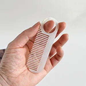 Acetate hair comb detail view, portable finger hole design with marble pattern texture.