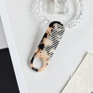 Detailed view of the stylish acetate hair comb with marble pattern and convenient ring handle.