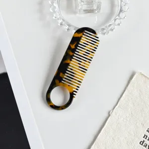 Acetate hair comb with classic tortoiseshell pattern and circular handle hole for daily use.