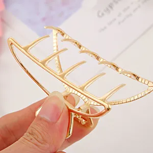 Detail shot of a minimalist gold metal hair claw clip, showing sturdy teeth design and shiny finish.