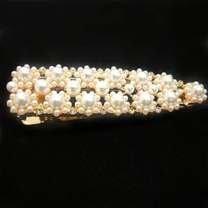 Pearl hairpin detail view, golden metal barrette with sparkling rhinestones for chic hairstyles.