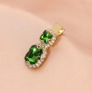 Close-up of the vintage green rhinestone hair clip showing the sparkling crystals and gold.