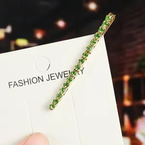 Green rhinestone hairpin detail, elegant gold metal hair clip, fashion hair accessory for women.