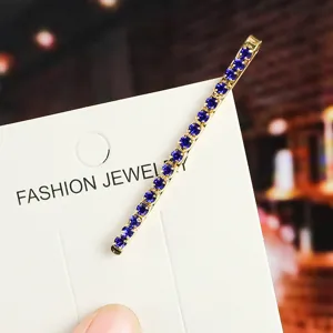 Detailed shot of blue rhinestone hairpin, elegant golden bobby pin on card display.