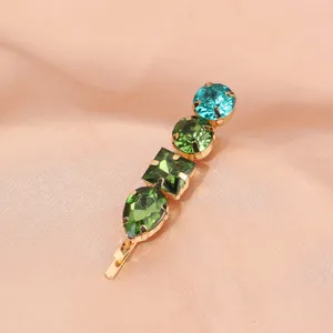 Detailed view of a vintage style green rhinestone hair clip with multi-shaped crystal stones.
