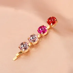 Detailed close-up of a stylish gold rhinestone bobby pin featuring gorgeous gradient pink stones.