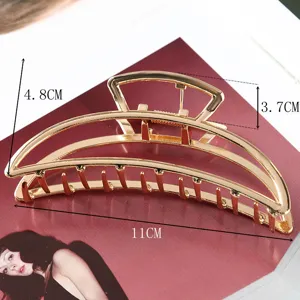 Detail view of a large gold metal hair claw clip with geometric cutout design, elegant fashion.