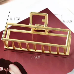 Golden metal hair claw clip detail shot showing geometric hollow design and precise size dimensions.