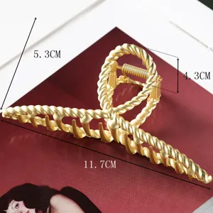 Close-up detail of the golden twisted metal claw clip showing fine textured surface.