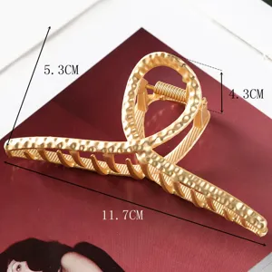 Metal hair claw clip for women, geometric twisted design, large gold hair catch accessory.