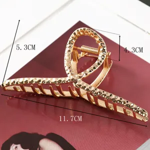 Golden metal hair claw clip with hollow geometric design, elegant hair accessory for women.