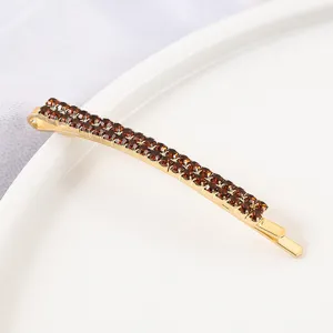 Detailed close-up of shiny gold-tone hairpin featuring double rows of sparkling brown rhinestones.