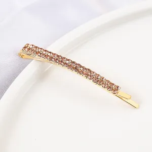 Gold rhinestone bobby pin detail shot, sparkling crystal hair clip, elegant side hair accessory.
