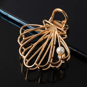 Gold metal hair claw clip for women, stylish shell design with elegant pearl decoration.