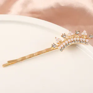 Gros plan d'une pince à cheveux couronne dorée ornée de perles et de strass étincelants.