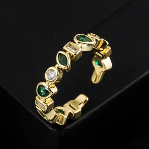 Gros plan de la bague ouverte plaquée or vintage avec des zircons verts et blancs.