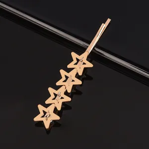 Vue détaillée d'épingle à cheveux dorée en métal avec quatre étoiles creuses connectées.