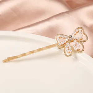Vue de détail de l'épingle à cheveux nœud en perles, élégante barrette dorée avec strass pour femmes.