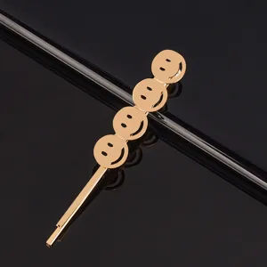Détail de pince à cheveux visage souriant en métal doré, épingle élégante pour look quotidien.