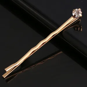 Détail de pince à cheveux dorée avec un strass étincelant et une belle finition métallique.