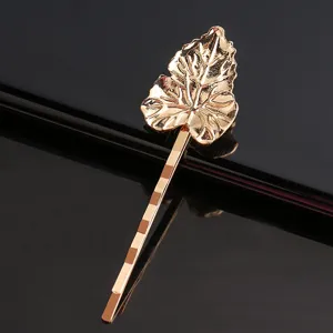 Vue détail pince à cheveux feuille dorée, texture élégante et finition brillante métal.