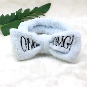 Nahaufnahme eines weichen blauen Plüsch-Make-up-Stirnbandes mit süßen OMG-Stickereidetails.