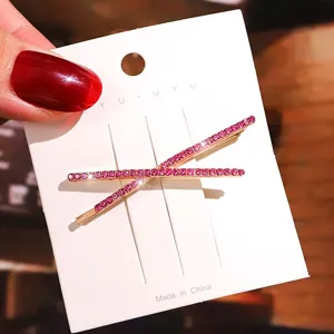 Primer plano detallado de la horquilla de pelo con strass cruzados y cristales rosados.