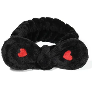 Nahaufnahme des schwarzen Plüsch-Haarbands mit roter Herzstickerei, weiches Kosmetikband.