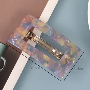 Gedetailleerde close-up van rechthoekige acetaat haarspeld met kleurrijk marmerpatroon.