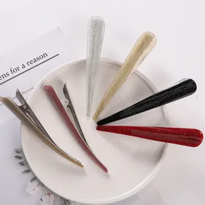 Close-up of glitter hair clips, shiny acrylic and metal duckbill clips for styling details.