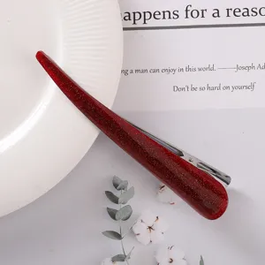 Red glitter hair clip detail showing the glossy acetate material and sturdy metal snap structure.