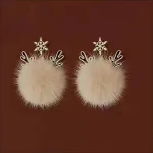 Close-up detail shot of winter Christmas deer antler and fluffy pom-pom stud earrings.