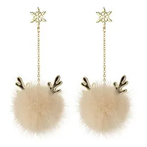 Close-up of elegant autumn winter reindeer plush ball earrings with gold snowflake studs.