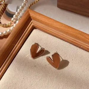 Detailed close-up of brown heart-shaped stud earrings with gold rim, elegant jewelry display.