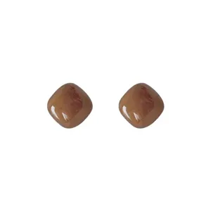 Detailed shot of minimalist brown square stud earrings, highlighting the glossy finish.