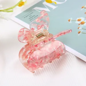 Pink acetate hair claw clip with cute butterfly design, stylish marbled hair accessory for women.