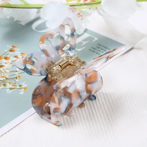Detail of butterfly hair claw clip with stylish marbled acetate pattern and metal spring.
