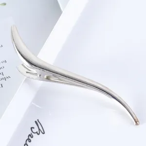 Detailed view of silver metallic S-shaped curved hair duckbill clip with brushed texture.