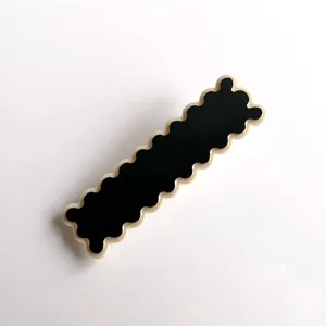 Close-up detail of a stylish black and white acrylic wavy hair clip, chic side pin.