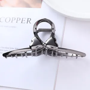 Close-up of dark metal hair claw with heart design, showing delicate texture and secure grip.
