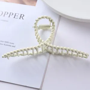 Detail view of the elegant off-white metal hair claw featuring a stylish twisted design.