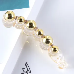 Close up detail of transparent resin banana hair clip featuring gold balls and sparkling stones.