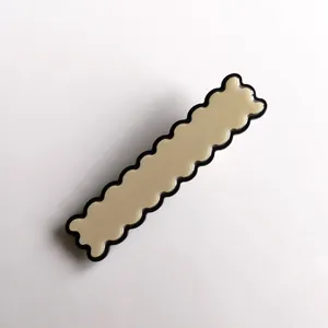 Closeup of stylish beige wavy acrylic hair clip with black border, chic daily hair accessory.
