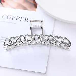 Detailed view of silver metallic hair claw clip with interlocking heart hollow design.