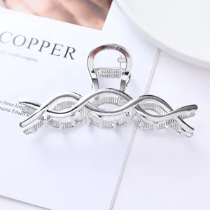 Detailed close-up view of silver metal hair claw clip with elegant cross design for styling.