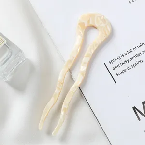 Detail de fourche a cheveux en acetate en U, design ondule elegant pour chignons et coiffure.